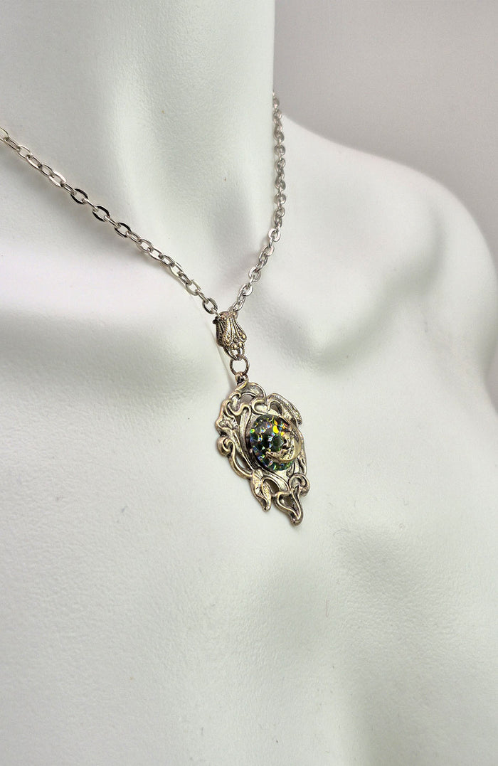 Sterling silver filled Victorian antique or reproduction work from original mold. The pendant features a silver vine design surrounding a central bright green & red iridescent antique Art Glass cabochon with a crescent moon motif.