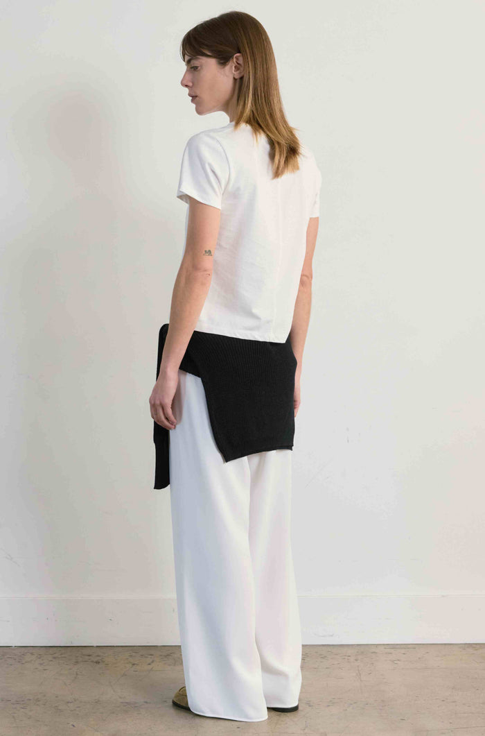 Woman wearing a white t-shirt and black and white pants against a plain background