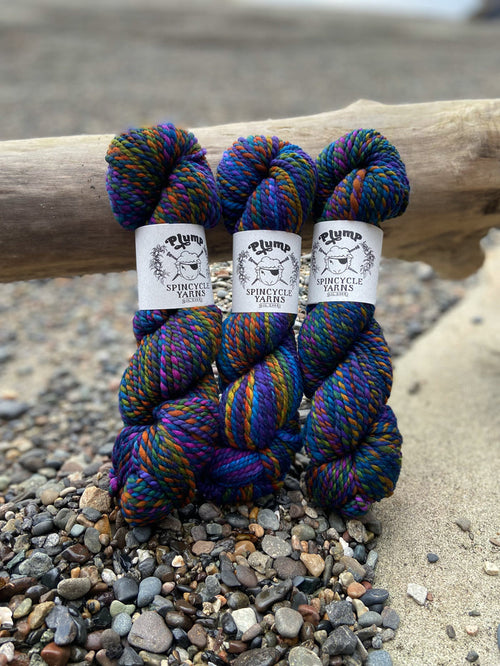 Skeins of Spincycle Plump Bulky weight yarn in dark rainbow color gradient colors