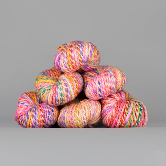 Skeins of Spincycle Plump Bulky weight yarn in pink, yellow, green, and blue color gradient