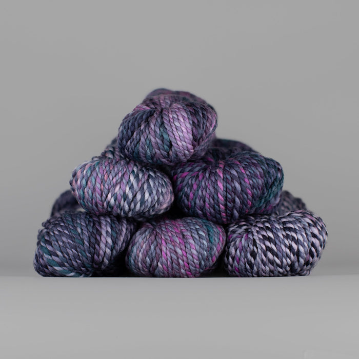 Skeins of Spincycle Plump Bulky weight yarn in purple, mauve, blue, black, and white color gradient